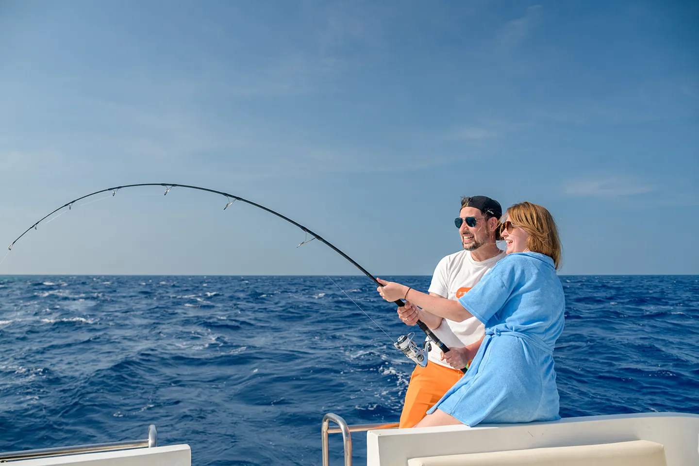 Junges Paar fischt gemeinsam vom Boot aus