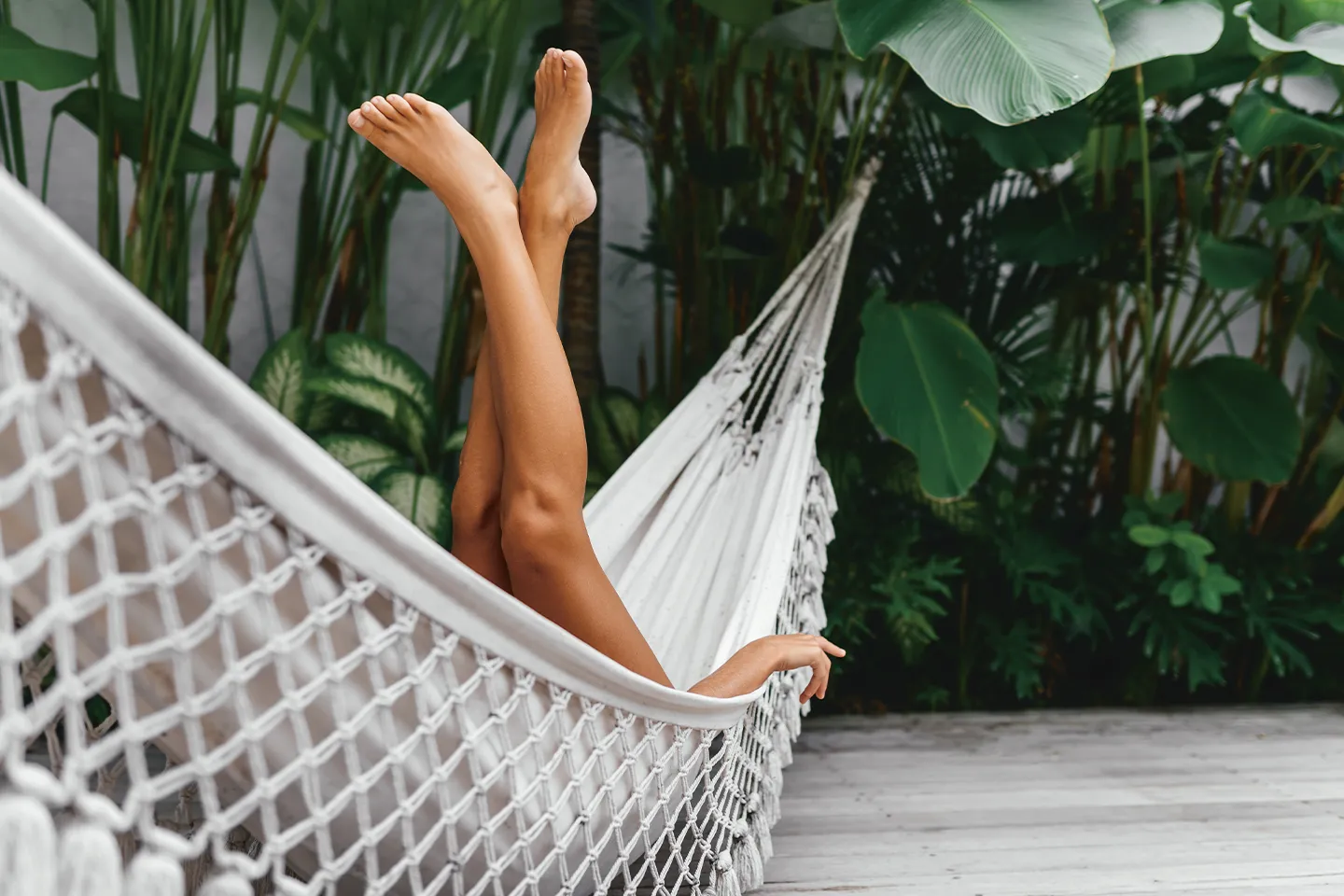 woman relaxes in hammock and stretches her legs upwards