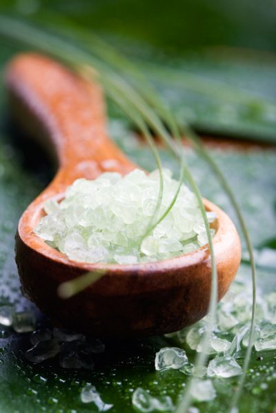 Green bath salt on wooden spoon